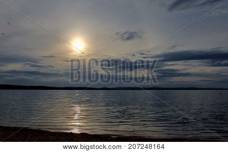 Hazy Sun Over The Lake Shines Through The Gray Clouds