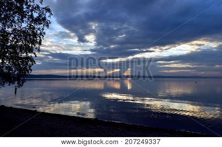 Sunlight Breaking Through Gray Clouds Over The Lake