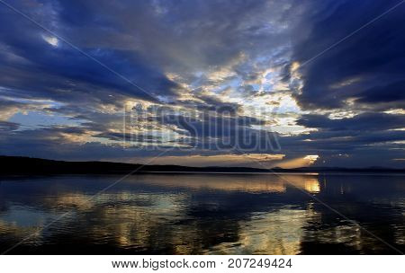Sunlight Breaking Through Gray Clouds Over The Lake