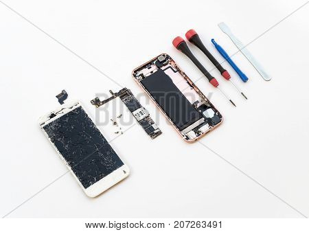 Disassembled cracked smartphone screen preparing to repair or replace new screen on white background