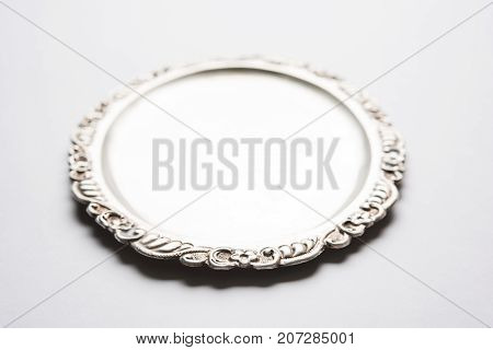 Stock photo of empty or blank silverware or oval shape plate with decorative border, isolated over white background, selective focus