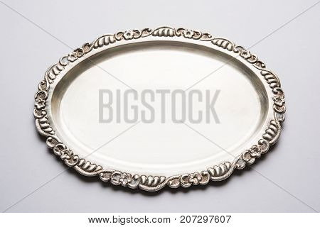 Stock photo of empty or blank silverware or oval shape plate with decorative border, isolated over white background, selective focus