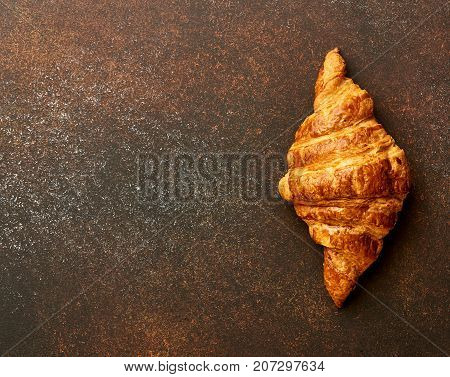 Croissant on brown concrete background. Bakery product on brown concrete background. Copy space.