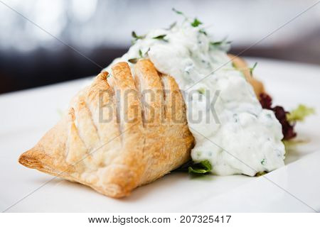Traditional russian pie - coulibiac. Baked puff pastry filled with smoked salmon, served with sour cream sauce