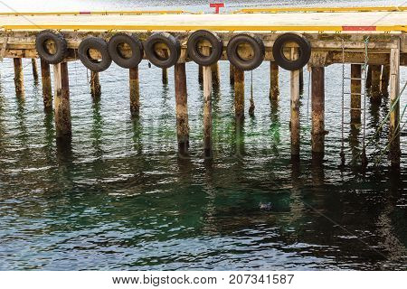 Pier lined with tires as fenders for the boats docking on them, close view, Harstad in Norway