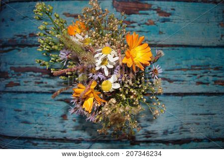 Wildflowers on a textured old blue board. Floral background. A wooden background with a shabby blue paint. Top view, flat lay. Flowers, spring, summer concept. March 8, mother's day background.
