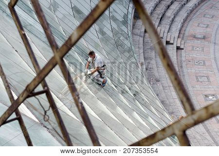 UKRAINEKIEV-SEPTEMBER 242017: Worker cleans the windows of an office building on Khreshchatyk Street.
