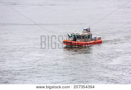 NEW YORK USA - Sep 18 2017: US Coast Guard patrol boat with officer manning gun on the bow patrolling East River during the 72th session of the UN General Assembly in New York City