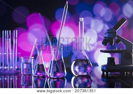 Laboratory concept. Beakers and microscope. Coloful bokeh background.