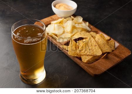 Beer In Glasses Closeup On The Concrete Table. Beer And Snacks Are Chips And Nachos With Cheese Souc