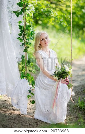 portrait of beautiful young blonde in a blue dress sitting on the sea shore