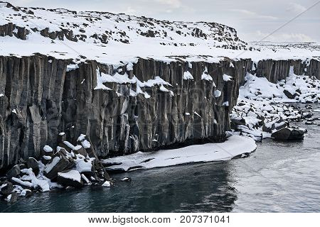 Majestic landscape of the river with the steep frozen rocky shore on the background of the cloudy sky in Iceland. Horizontal.