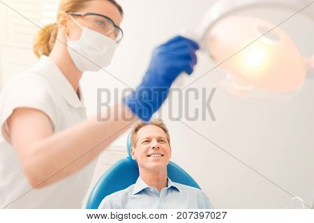I am ready. Selective focus on a cheerful mature gentlemen grinning broadly while relaxing on a dental chair and waiting for his teeth to be treated at a dental clinic.