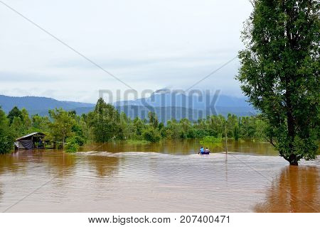 Phitsanulok Thailand- September 162017: Flash flood by red turbid water flows down from the mountain due to torrential rain with people paddling boats.