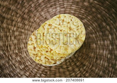 Yellow flat round corn crackers on whicker place mat background.