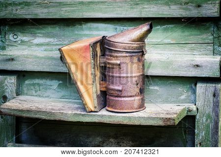 Beekeper stuff smoker on honey bee hive in the garden