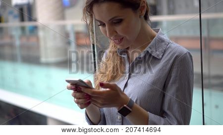 Attractive smiling woman using a smartphone in a moving elevator