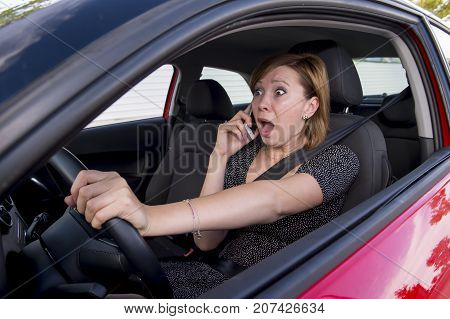 young beautiful woman driving car while texting and using mobile phone distracted in risk and danger of accident crash by distraction and not paying attention to traffic