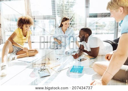 Working day. Delighted enthusiastic colleagues discussing a new start up while exchanging opinions and expressing cheer