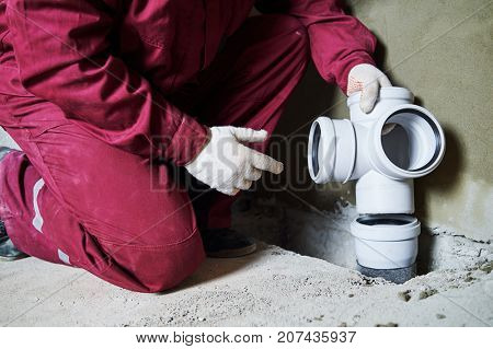 Plumber worker installing sewage pipes in sewerage system