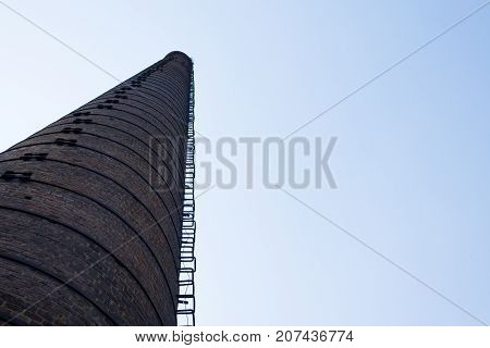 Bottom view of the old brick high pipe of the old factory.
