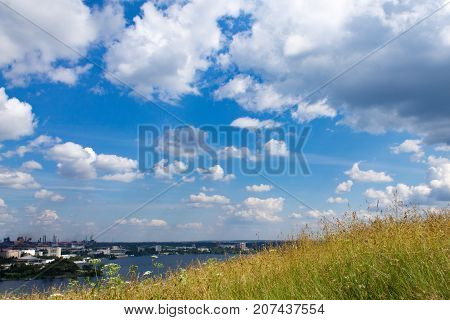 Meadow on a hill by the lake in an industrial city.