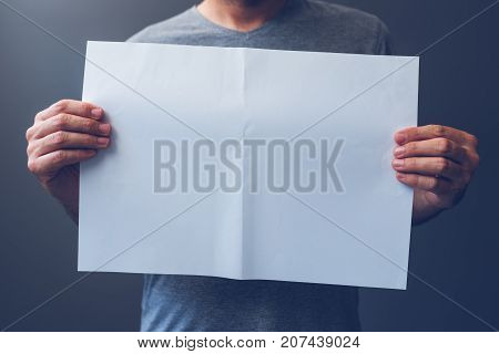 Casual man holding blank A3 paper spread as copy space for magazine and newspaper text or graphic design mock up
