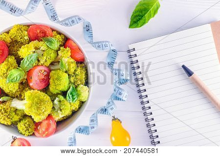 Top View Salad Bowl With Cherry Tomatoes, Broccoli, Measuring Tape And Diet Book On The White Wooden