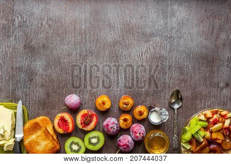 Oatmeal with plums, kiwi and peach, toast with butter and honey on a wooden table. A cup of black tea. The concept of a healthy breakfast. Top view. Copy space. Still life. Flat lay