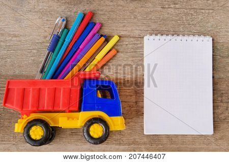 Open white notepad with colorful felt-tip pens and ball pens on the wooden table. Space for text
