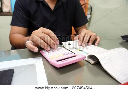 Close up hands of man work as a car paint mixing technician was to examine accounts and use pink calcullator
