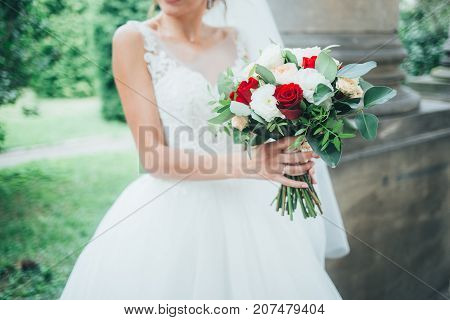 Young beautiful bride holds a bouquet hands