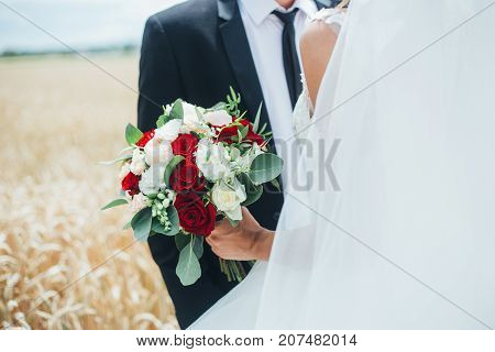 A young beautiful bride and groom holds a bouquet