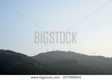 Wide angle view of multiple radio transmission towers and power lines on the forested hills. Nobeoka Miyazaki Kyushu Japan. Energy and environment concept.