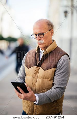 Wireless Technology Keeps My Daily Tasks Streamlined. Shot Of A Senior Man Sitting Outdoors And Look