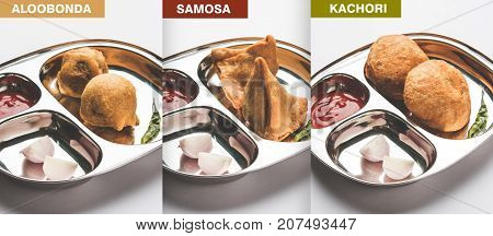 Samosa , kachori and alubonda or batata vada - Indian deep fried junk but tasty food or snacks served in stainless steel plate over white background with tomato ketchup and green fried chilly