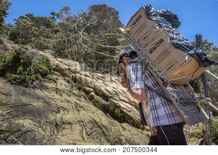 Ranau,Sabah-March13,2016:Mountain porter carrying a heavy backpack to Laban Rata of the majestic Mount Kinabalu in Ranau,Sabah Borneo,Malaysia.