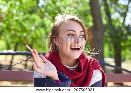 The femae artist paints a picture in the sunny day in a good mood. Young woman drawing a picture in autumn park.