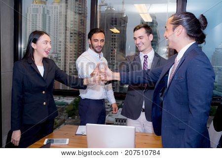 Portrait of happy business partners looking at camera with smiles and geture of teamwork.