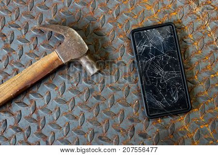 Broken mobile screen and hammer on old metal diamond plate or old checkered steel plate with rusty.