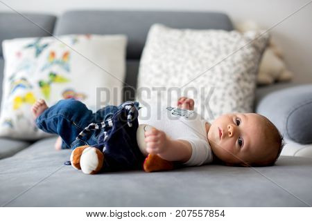 Adorable little baby boy playing with toy looking curiously at camera