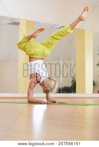Beautiful sporty fit yogi woman practices yoga asana Vrischikasana Scorpion pose in the yoga class