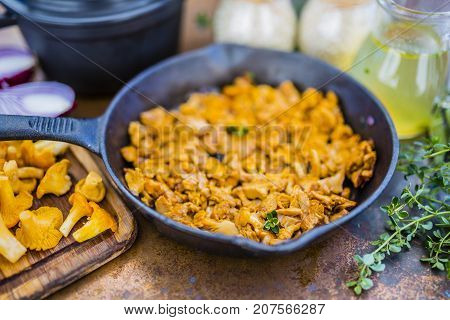 Chanterelle mushrooms with herbs on a frying pan.