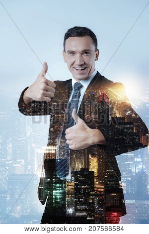 Undeniable success. Waist up of cheerful director keeping two thumbs up while being amused