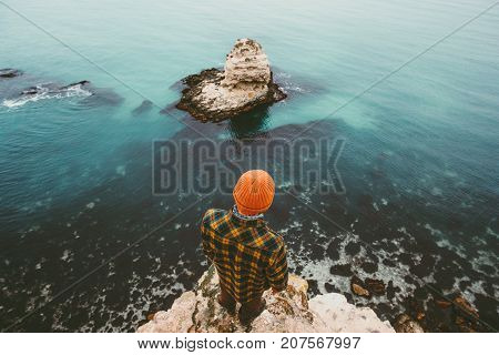 Man traveler standing on cliff above sea aerial view alone Travel Lifestyle concept adventure vacations outdoor Melancholy solitude emotions