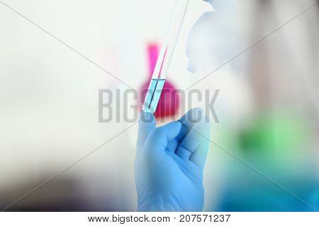 A male chemist holds test tube of glass in his hand overflows a liquid solution of potassium permanganate conducts an analysis reaction takes various versions of reagents using chemical manufacturing
