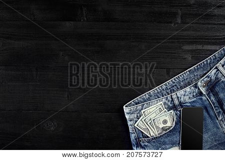 Cash and smart in your jeans pocket. Still life. Copy space. Top view on black background