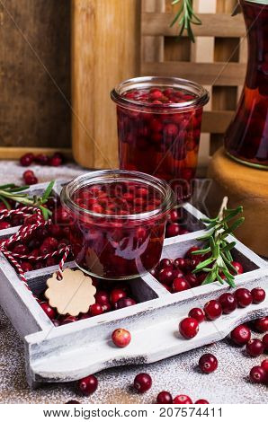 Cranberries with the syrup in glass on wooden background. Selective focus.