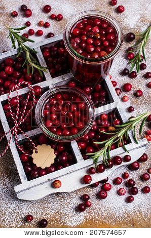 Cranberries with the syrup in glass on wooden background. Selective focus.