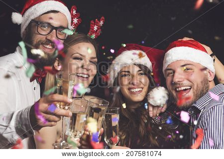 Four young people on a New Year's eve party making a toast at midnight